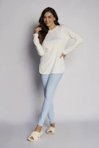 Modelo vestindo o Pijama Feminino Positive Off-White com blusa estampada de manga longa e calça canelada azul bebê.